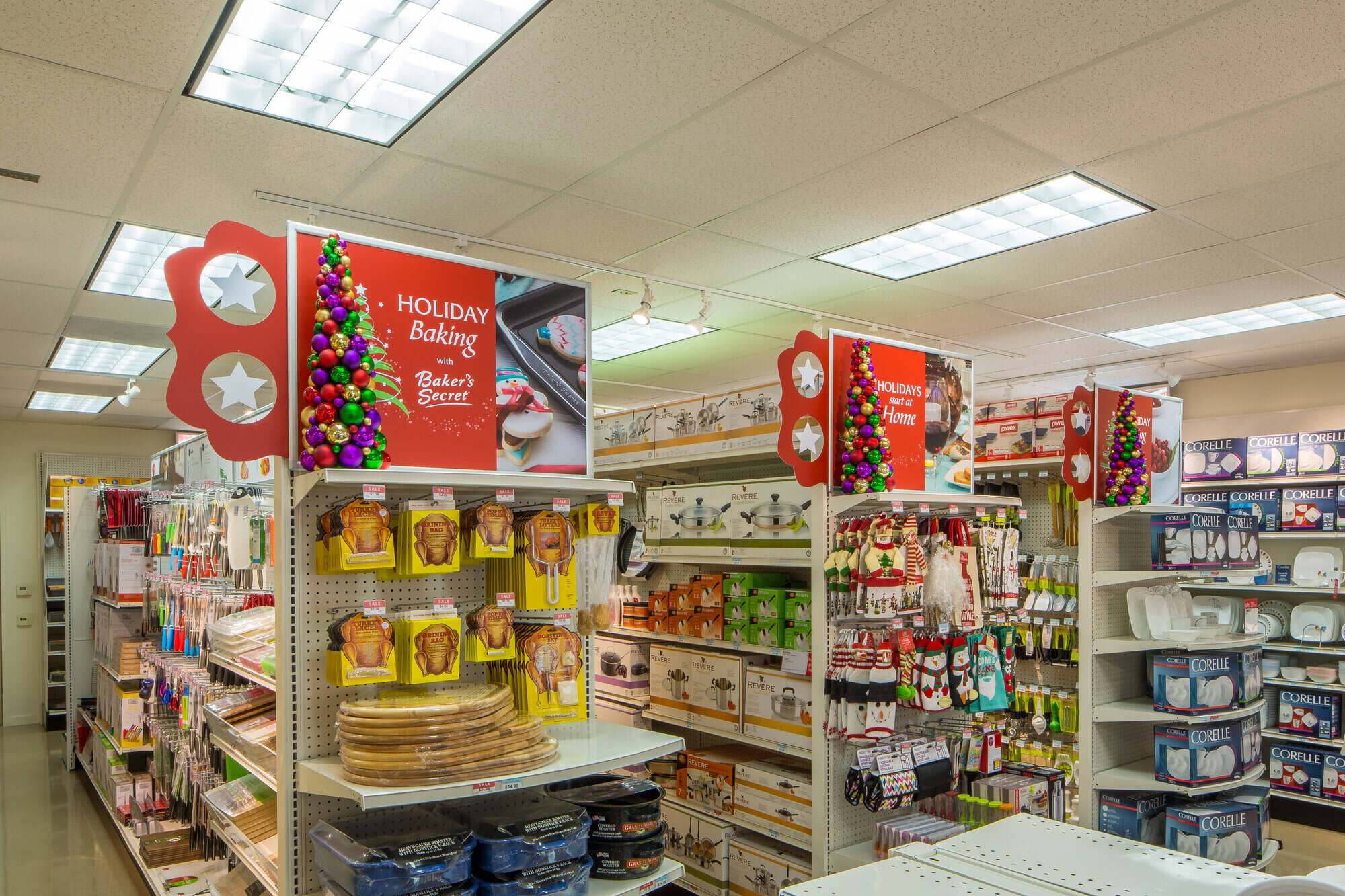 Holiday-themed end caps group together similar items. One display features tools needed for roasting a turkey. The other features seasonal oven mitts, towels and home decor.